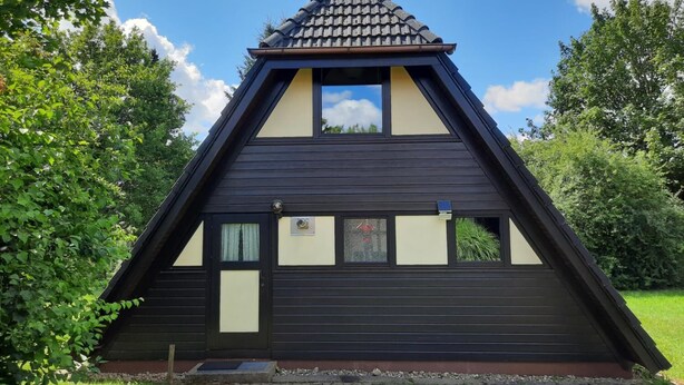A triangular building with a sloped roof, a small window, and a door. - Holiday park - Winnetou (Waldbrunn)
