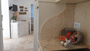 A kitchen with a built-in stove, a basket of vegetables, and a TV mounted on the wall. - Apartment- Iris - One Bedroom Apartment, Sleeps 4 (Marina di Castagneto Carducci)