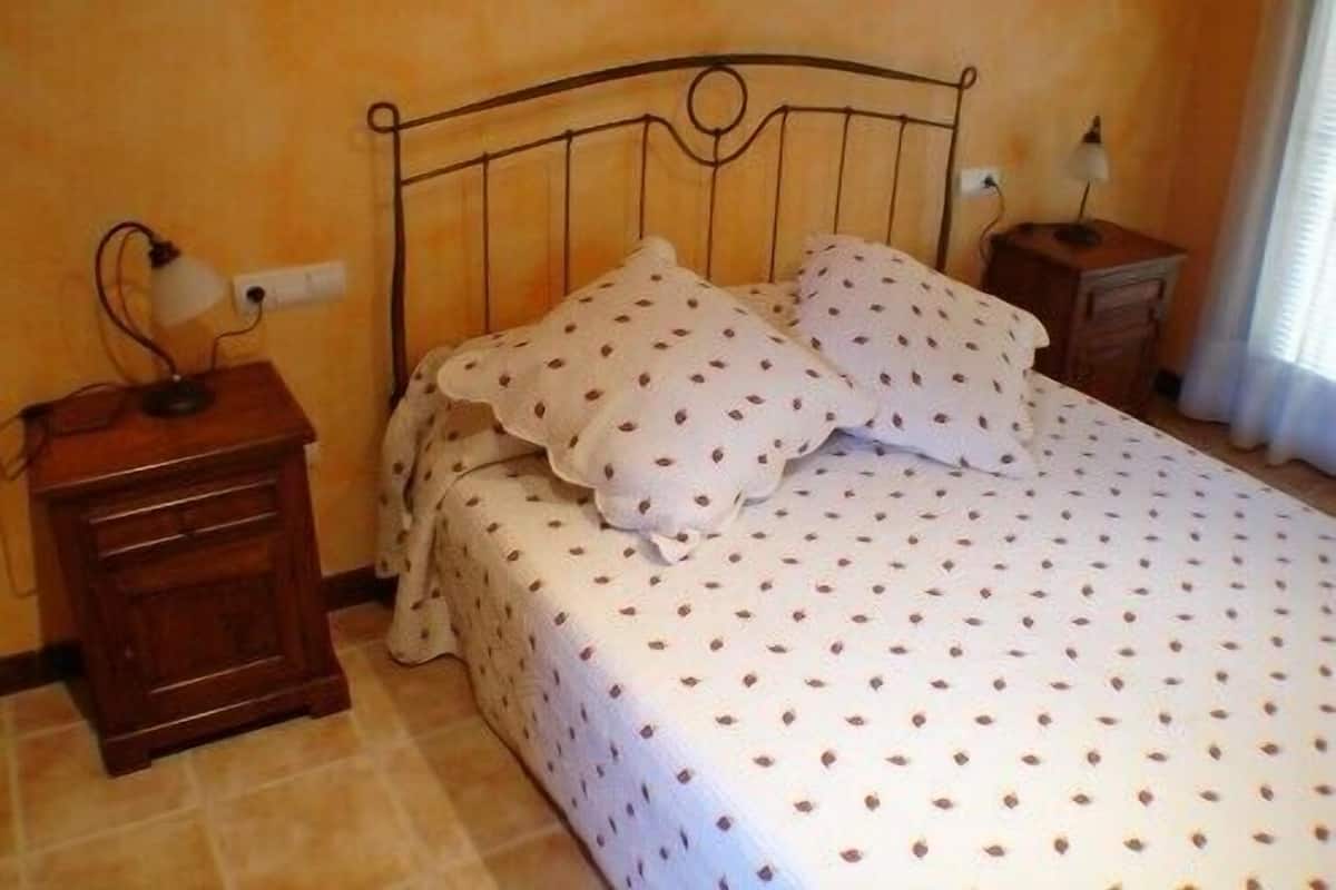 A bedroom with a bed, two nightstands, and a lamp on each nightstand.