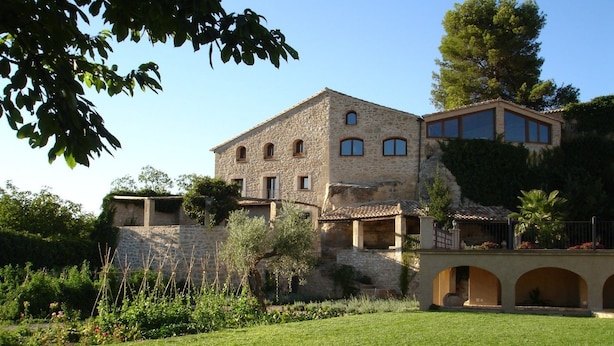 A stone building with multiple windows and a courtyard with a lawn. - Hotel Hort De Fortunyo (Arnes)