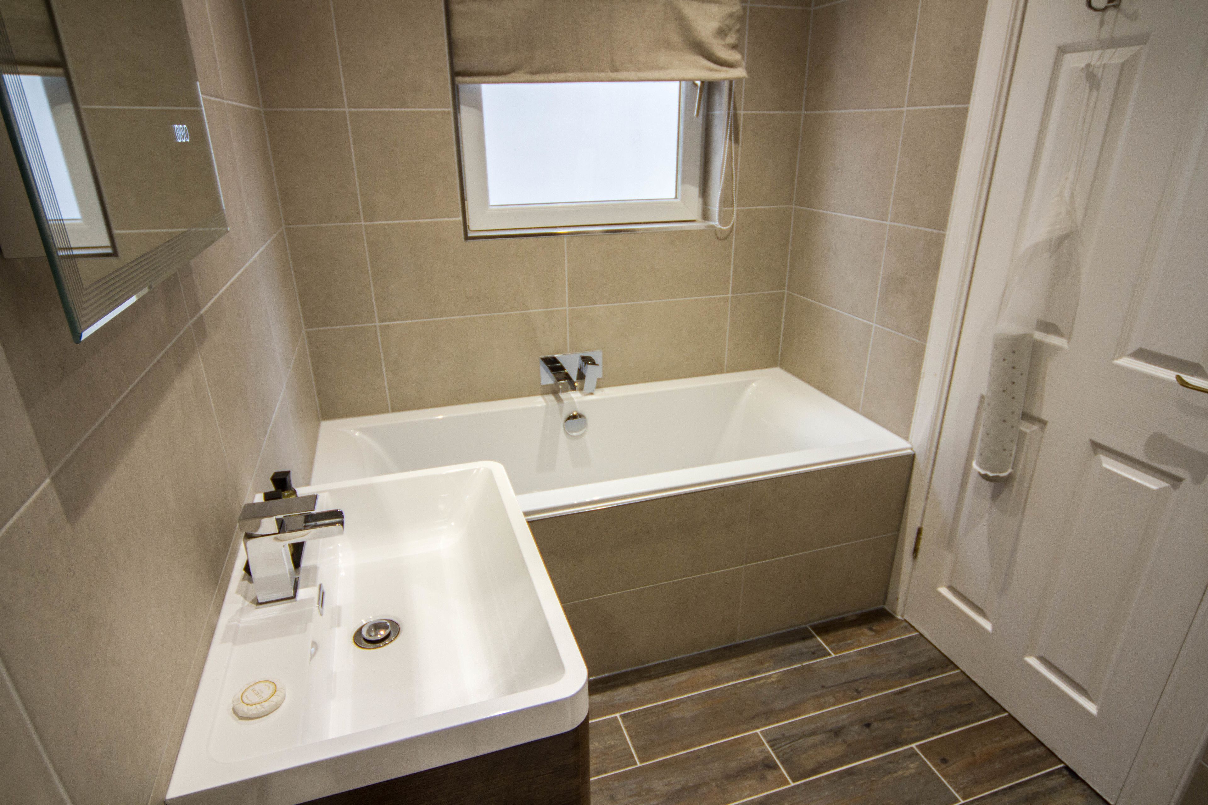 A bathroom with a bathtub, a sink, and a window.