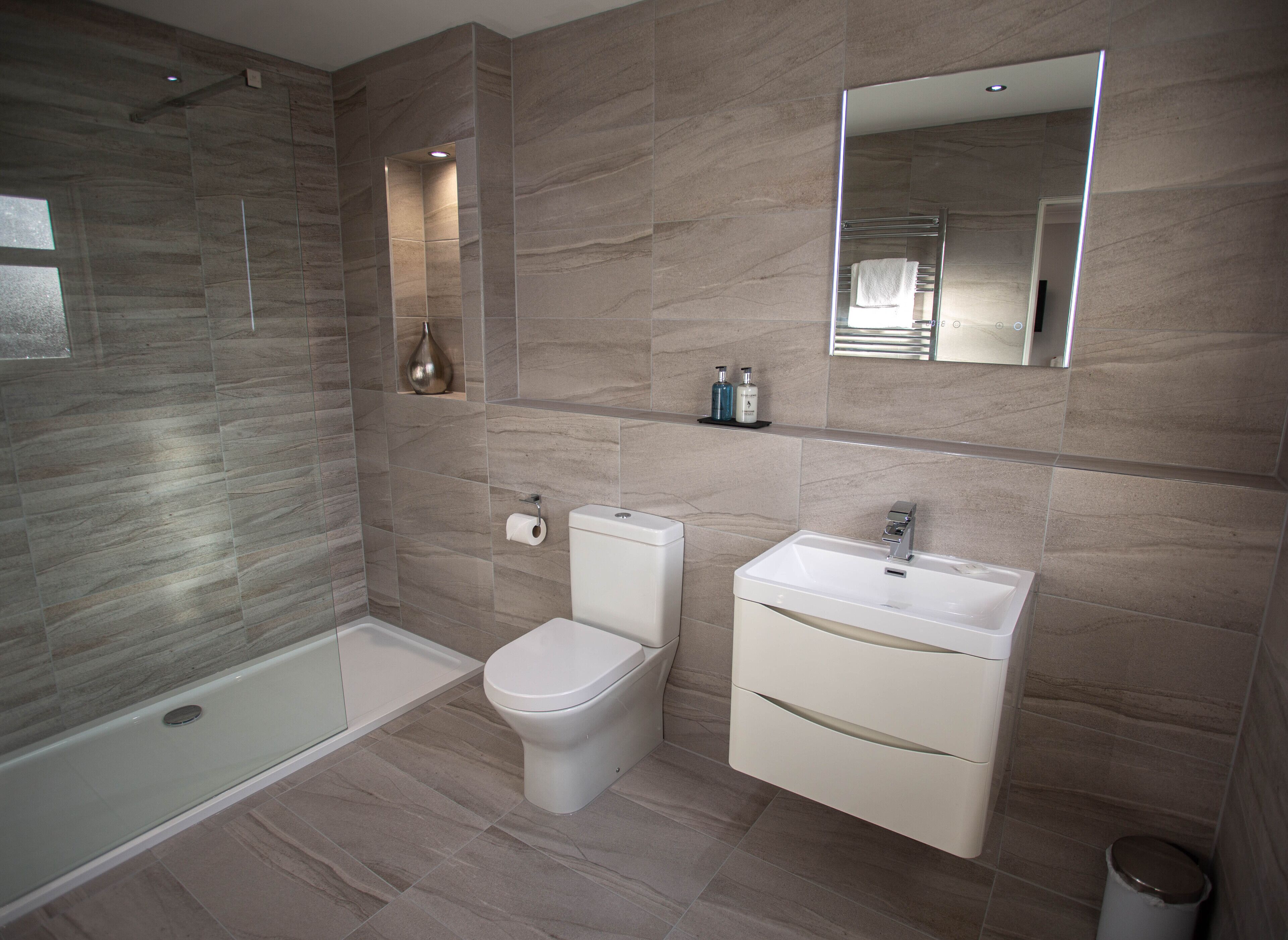 A modern bathroom with a glass-enclosed shower, a toilet, and a sink with a mirror above.