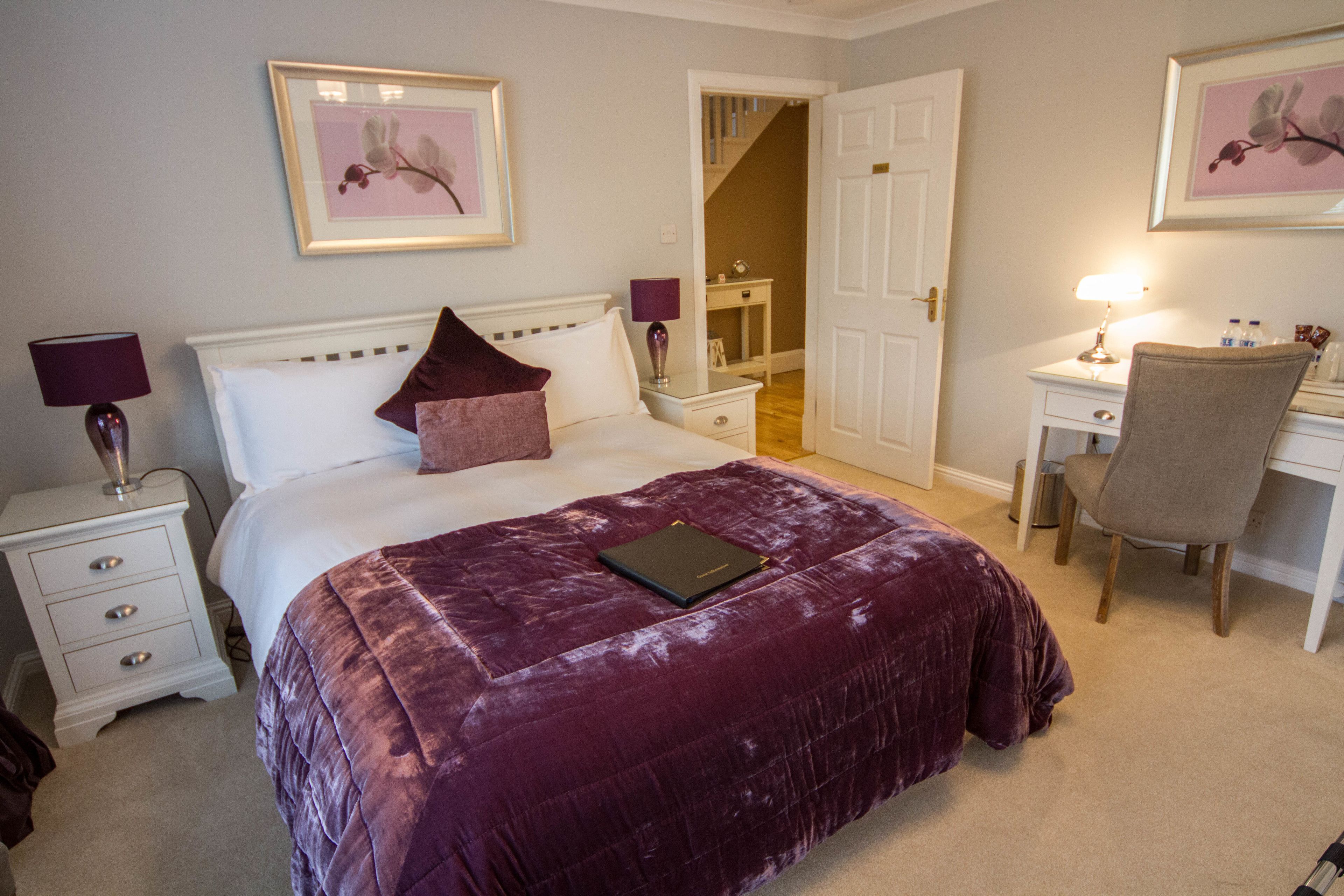 A bedroom with a bed, bedside tables, a desk, and a chair.