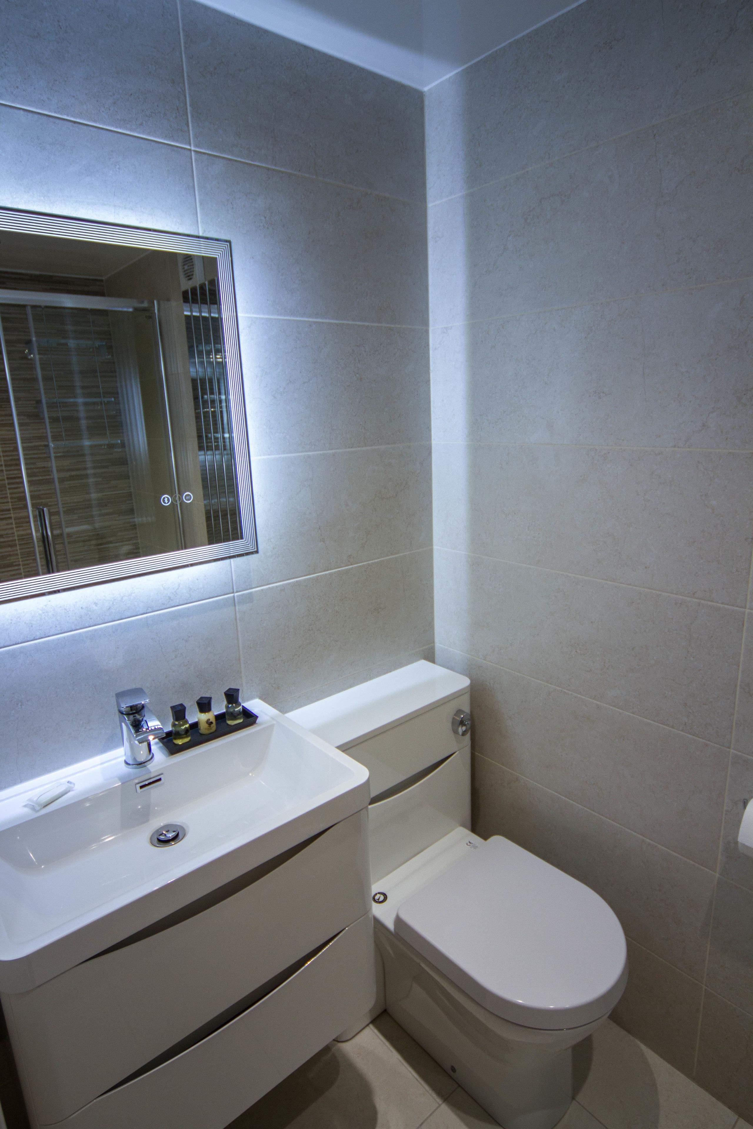 A bathroom with a white sink, mirror, and toilet.
