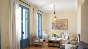 A living room with a sofa, armchairs, a coffee table, and a painting on the wall. - Villas Armeno (Lefkada)