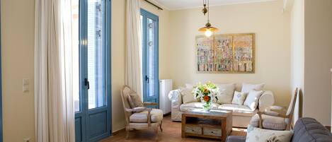Una sala de estar con un sofá, sillones, una mesa de centro y un cuadro en la pared.