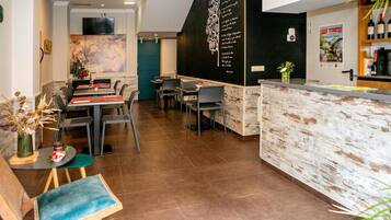 Un restaurante con una pared de pizarra, una zona de bar y un área de comedor con mesas y sillas.