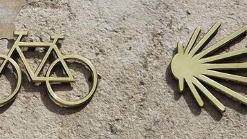 A bicycle and a sun symbol on a textured wall.