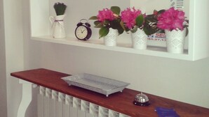 Un estante blanco con plantas en macetas y un reloj.