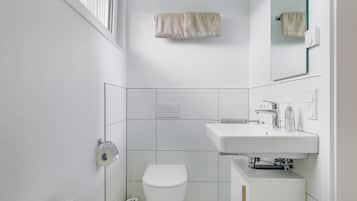 A modern bathroom with a toilet, sink, and towel hanging on the wall.