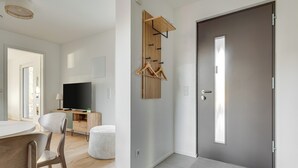 Una sala de estar moderna con una televisión de pantalla plana, muebles de madera y una puerta gris.