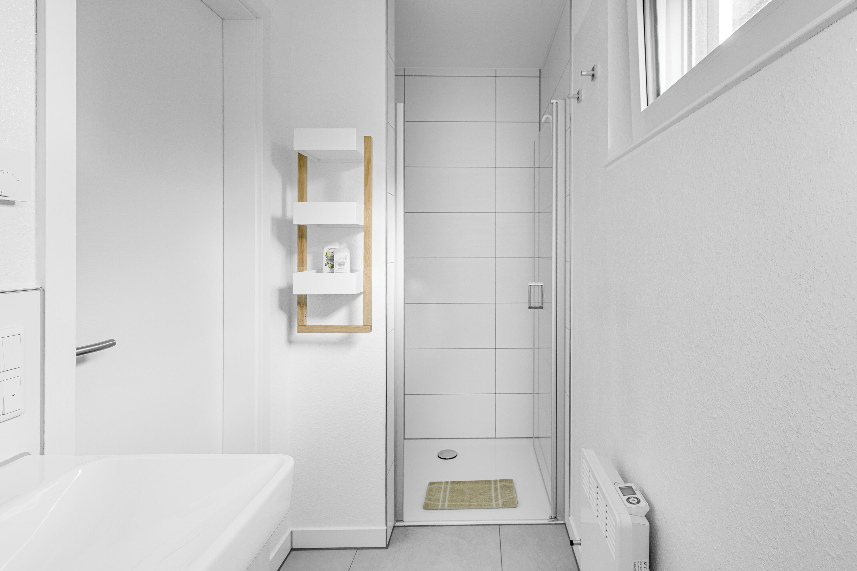 Une petite salle de bain comprenant une douche, des toilettes et une petite étagère.