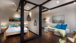 A modern bedroom with a wooden bed, a white sofa, and a dining table. - Haus Biederstaedt (Ottersberg)