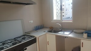 Une cuisine équipée d’une cuisinière à gaz, d’un évier et d’une fenêtre.