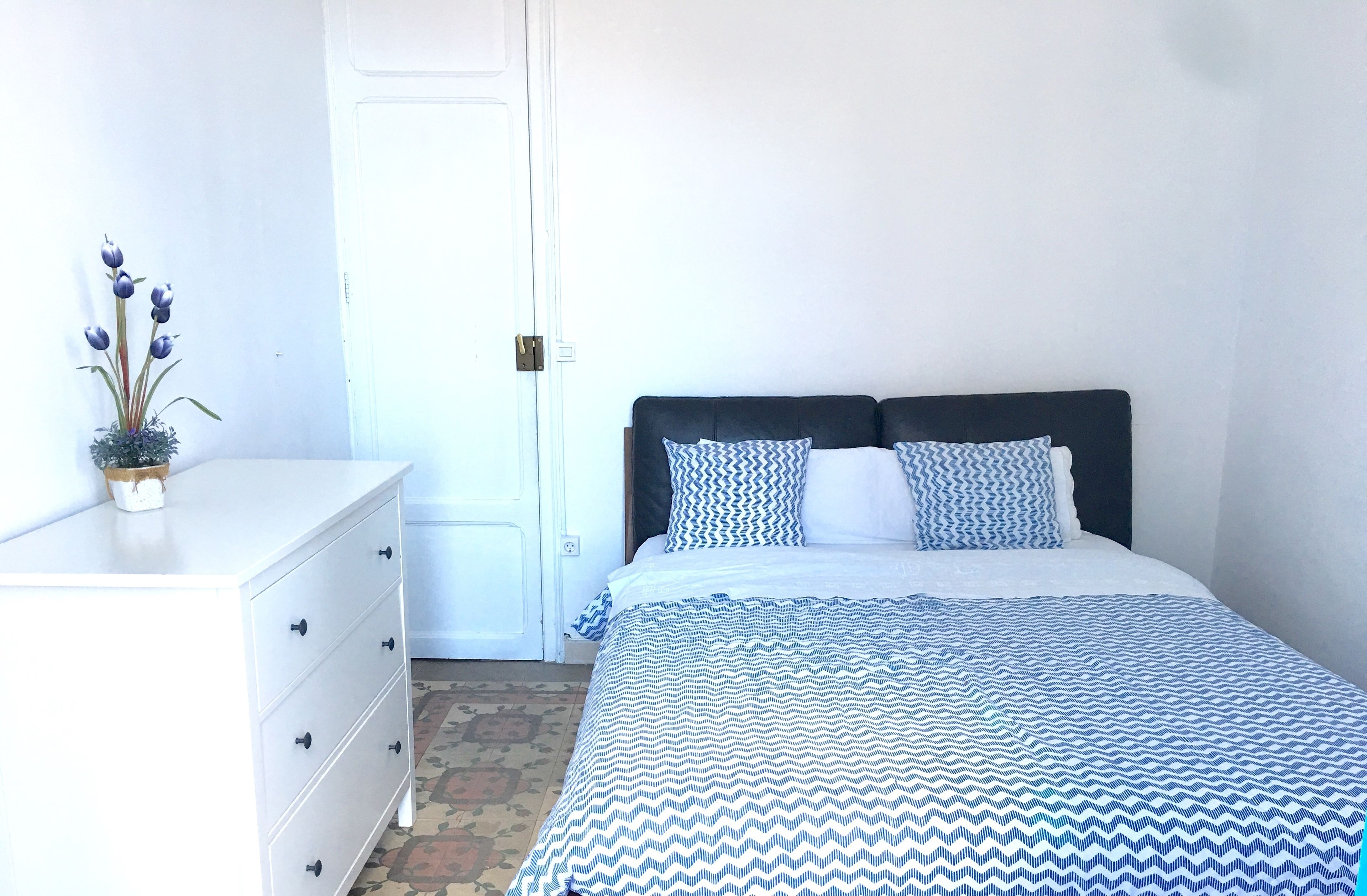 Een slaapkamer met een bed, een kaptafel en een potplant.