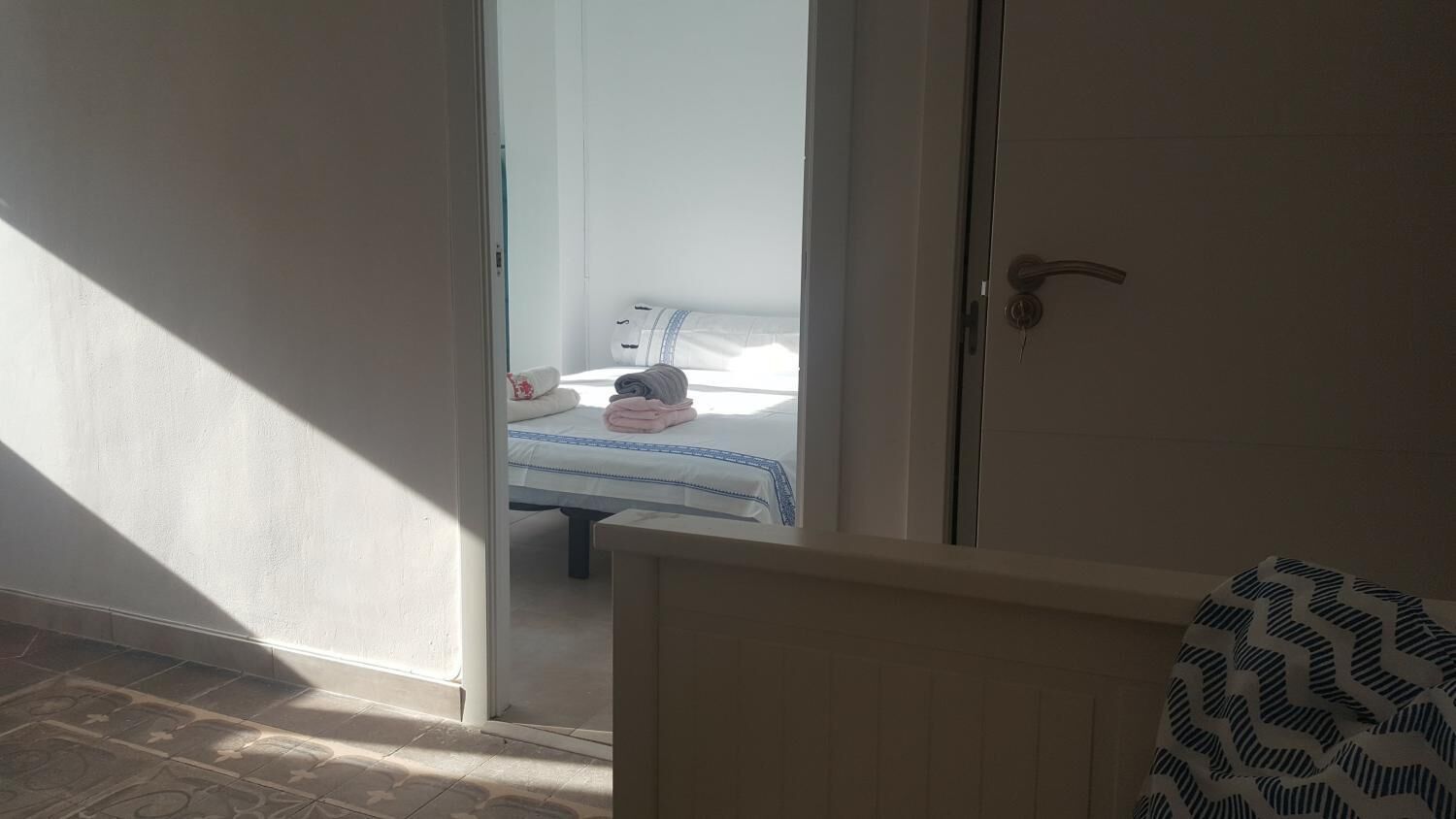 Una habitación con una cama, una puerta y vista a otra habitación.