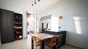 Una cocina moderna con una mesa de comedor y sillas, un horno empotrado y un mueble de madera oscura con estantes.