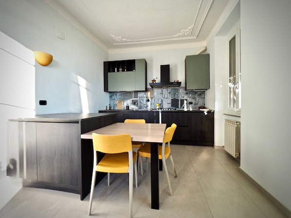 A modern kitchen with a central island, dark cabinetry, and yellow chairs.