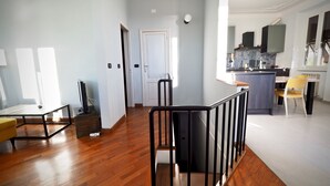 Amplia sala de estar con pisos de madera, una escalera y una cocina con diseño moderno.