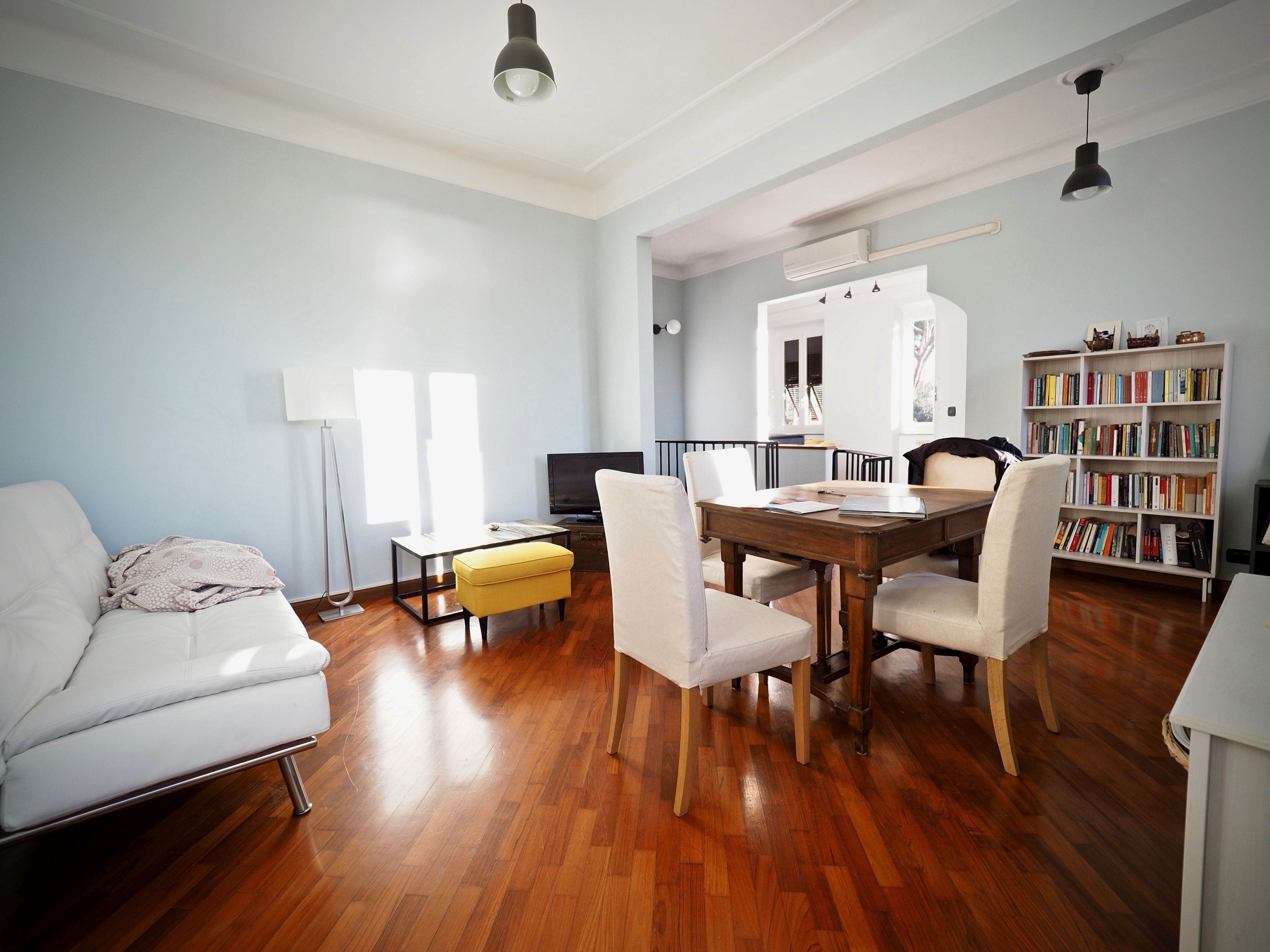 Ein modernes Wohnzimmer mit einem weißen Sofa, einem Holzesstisch und einem Bücherregal.