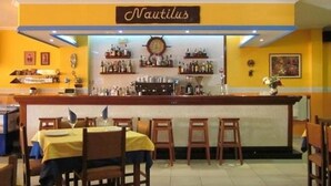 Un área de bar con un cartel que dice "Nautilus" y estantes llenos de botellas.