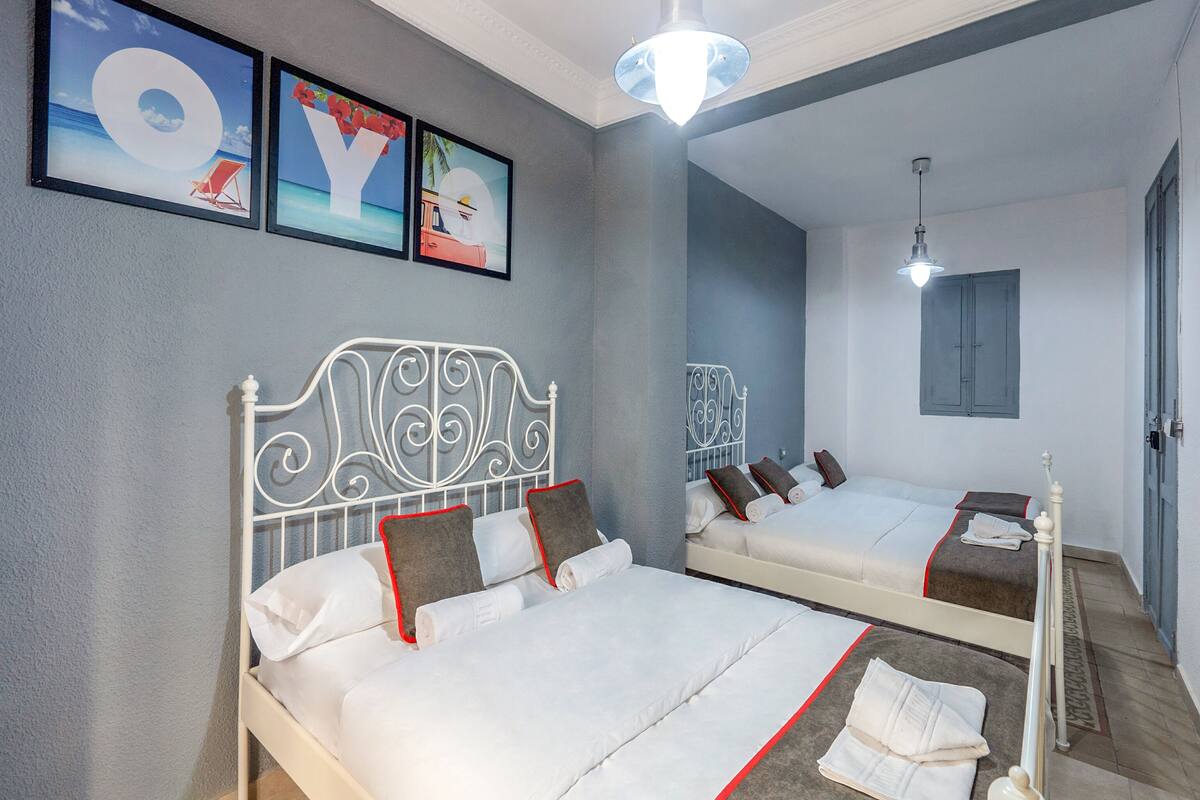 A hotel room with two beds, a mirror, and artwork on the wall.