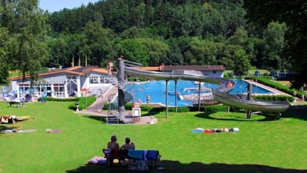 Een waterpark met een grote glijbaan, een zwembad en een gebouw met een rood dak.