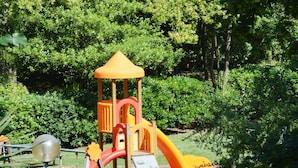 A playground with a slide and climbing structures, surrounded by greenery. - Hotel Athena (Pesaro)