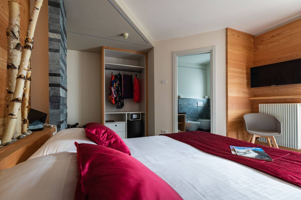 A hotel room with a bed, a wardrobe, a bathroom, and a television.