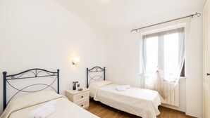 A bedroom with two single beds, a bedside table with a lamp, and a window with sheer curtains. - Semi detached Villa Country (Vieste)