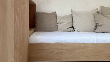Een slaapkamer in loftstijl met een houten platformbed, wit beddengoed en een schuin dak.