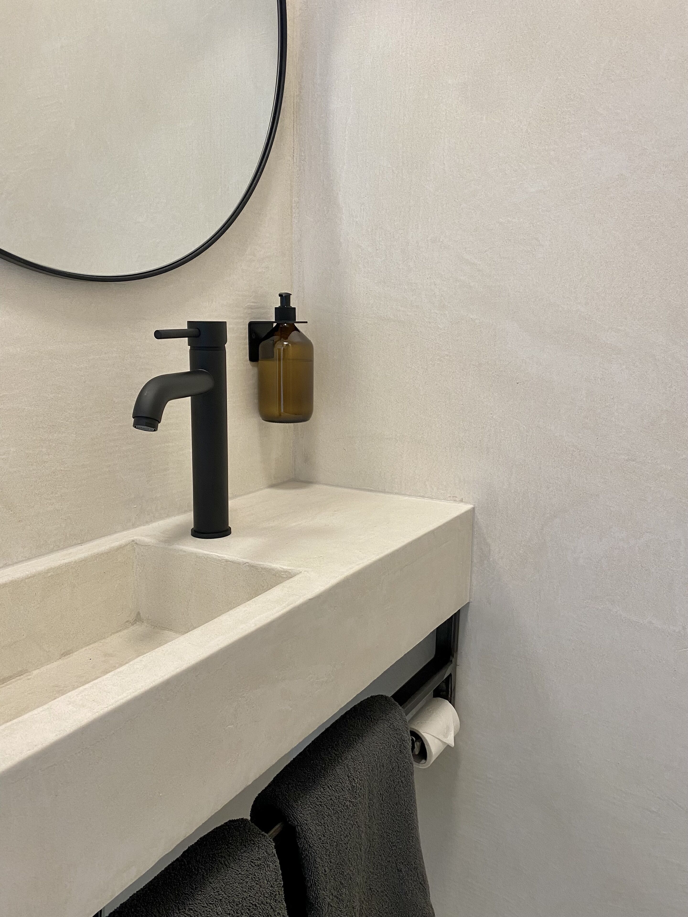 Un bagno con un lavandino moderno, un dispenser di sapone e un asciugamano su un porta-asciugamani.