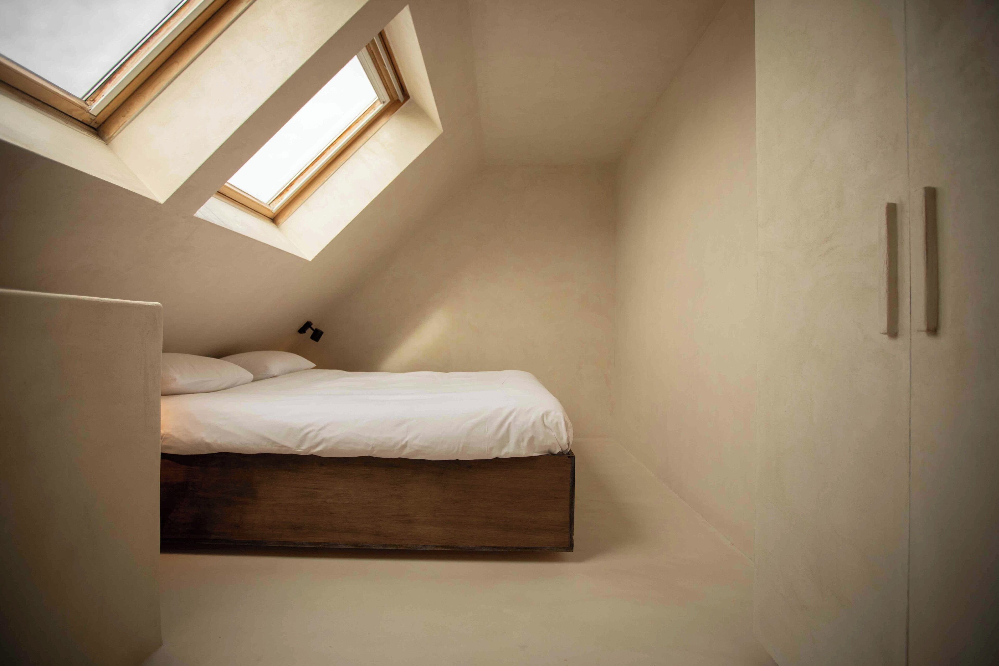 A bedroom with a skylight, a bed, and a wardrobe.