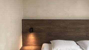 A bedroom with a wooden headboard, a bedside table, and a wall-mounted light.