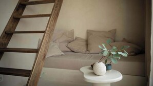 A wooden ladder, a sofa with cushions, and a small table with a plant and a cup.