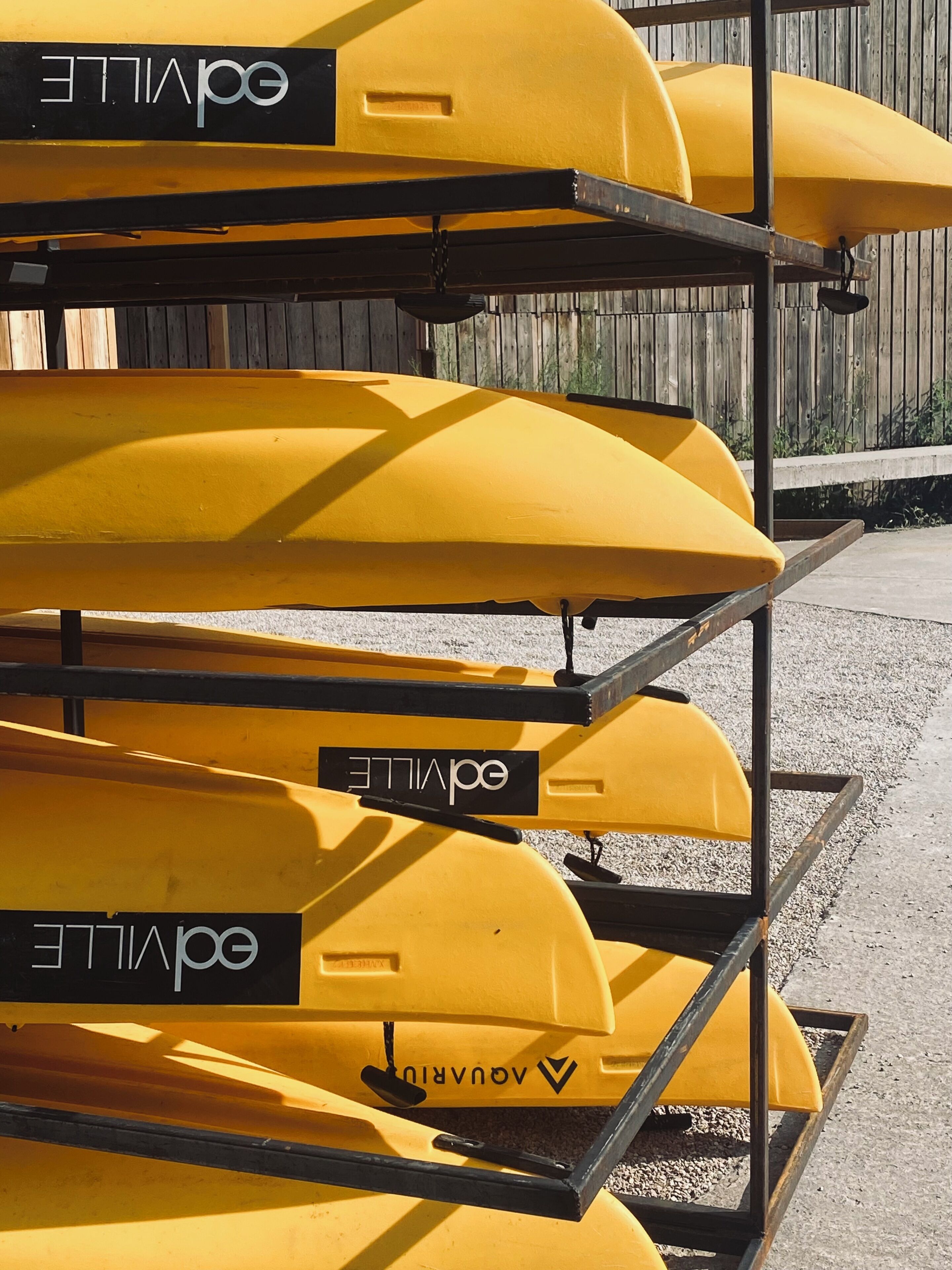A rack of yellow kayaks with the brand name visible on each.
