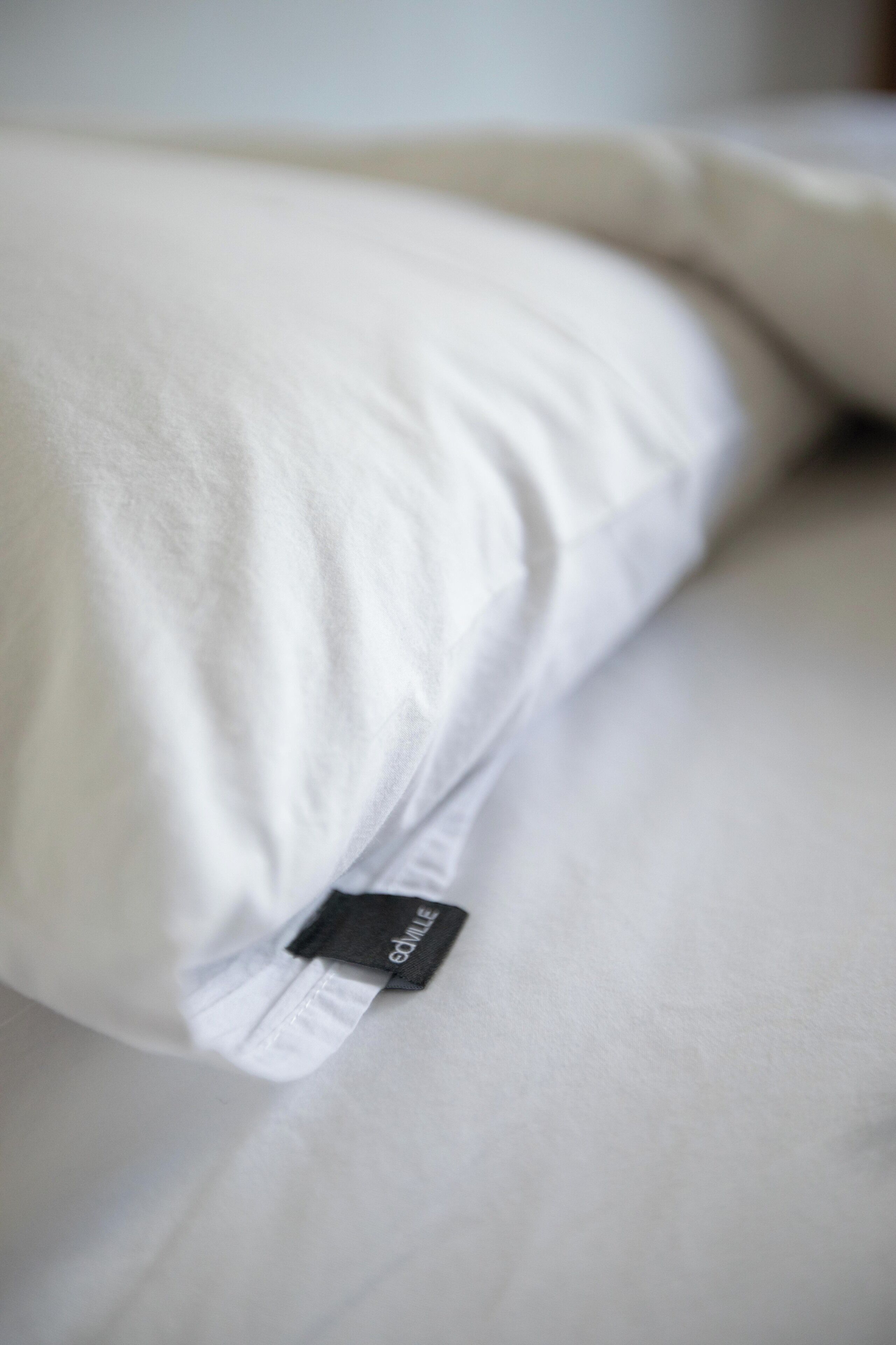 A pillow with a tag on a bed.