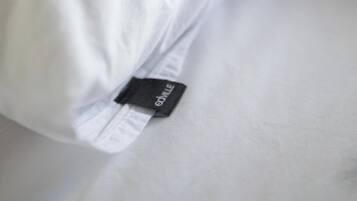 A pillow with a tag on a bed.