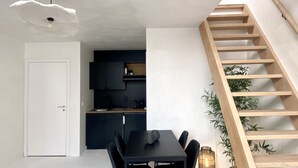 A modern kitchen with dark cabinets and a wooden staircase.