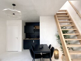 A modern kitchen with dark cabinets and a wooden staircase.