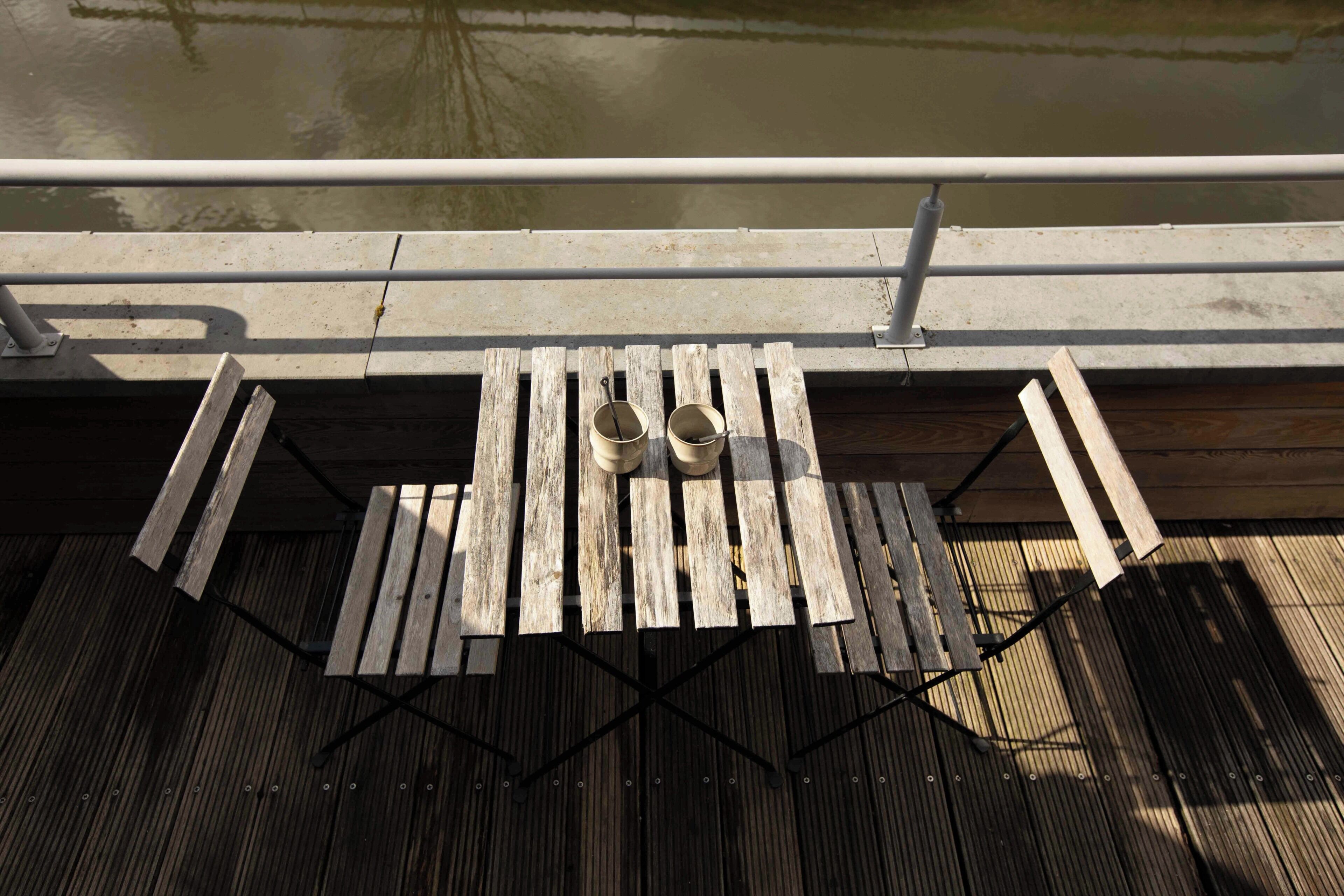 Un pontile in legno con un tavolo e due bicchieri di metallo.