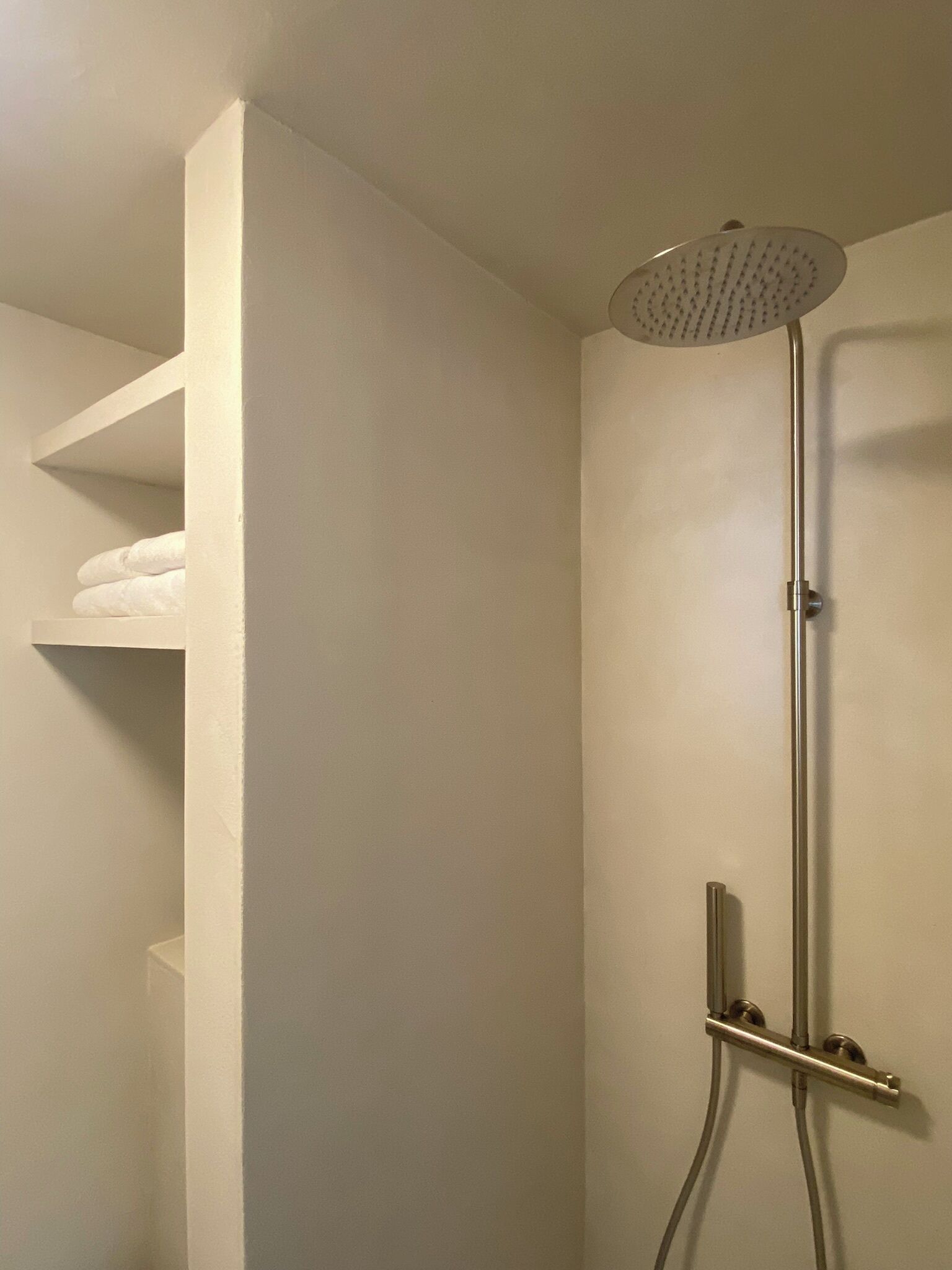 Une douche moderne dotée d’un pommeau de douche à main et d’un panneau de commande fixé au mur.