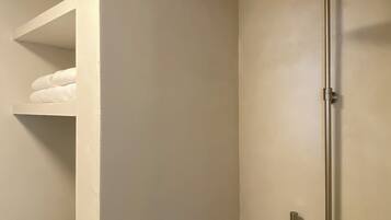 Une douche moderne dotée d’un pommeau de douche à main et d’un panneau de commande fixé au mur.