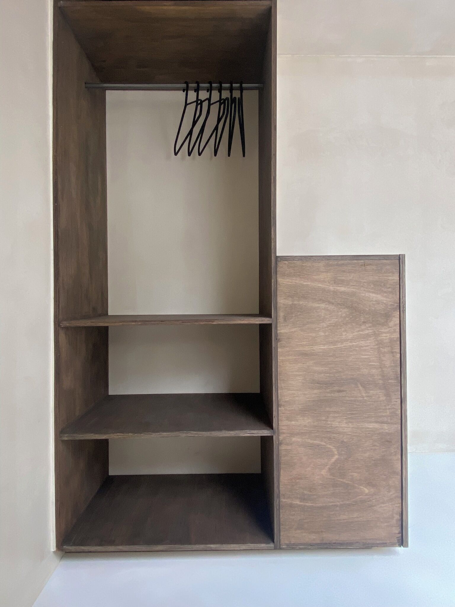 A wardrobe with three shelves and a hanging rod.