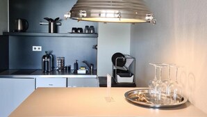 A modern kitchen with a central island, a coffee machine, and a wine glass holder. - Rheinblick Appartments (Cologne)