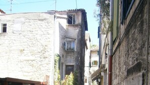 A narrow street with stone buildings, outdoor seating for cafes, and people dining. - Apartments and Rooms Djanovic (Split)