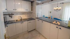 A modern kitchen with white cabinets, a built-in dishwasher, and a granite countertop. - Bella Panoramica - Two Bedroom Apartment, Sleeps 4 (Roses)