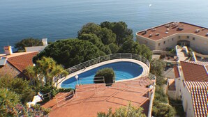 A rooftop swimming pool with a curved design, surrounded by trees and buildings with red-tiled roofs. - Bella Panoramica - Two Bedroom Apartment, Sleeps 4 (Roses)