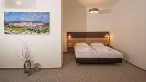 A modern hotel room with a large bed, a wooden headboard, and a framed picture of a castle on the wall. - Boutique-Hotel Kronenstuben (Ludwigsburg)