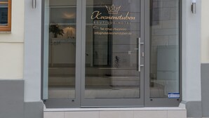 A hotel entrance with a glass door, a crown logo, and contact information. - Boutique-Hotel Kronenstuben (Ludwigsburg)